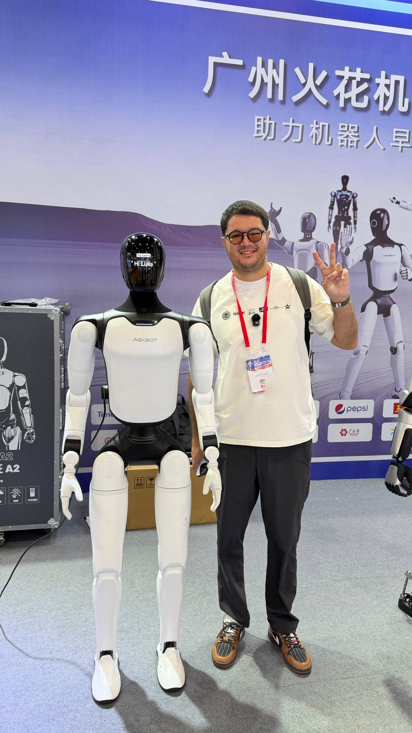 Akmal Ahmedov beside an AGIBOT humanoid robot at the exhibition in Guangzhou